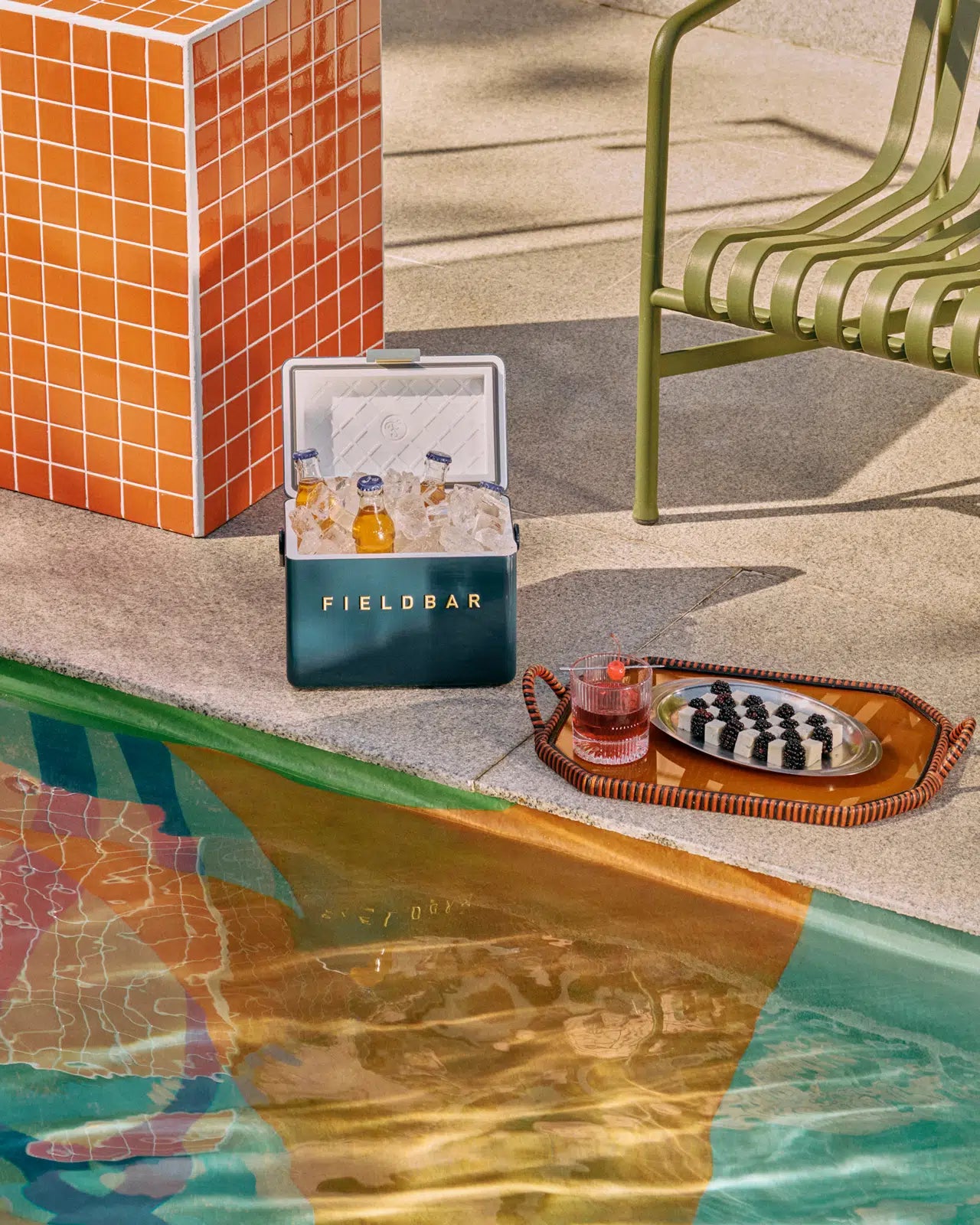 Cooler box FIELDBAR by a poolside with a chair and chessboard.